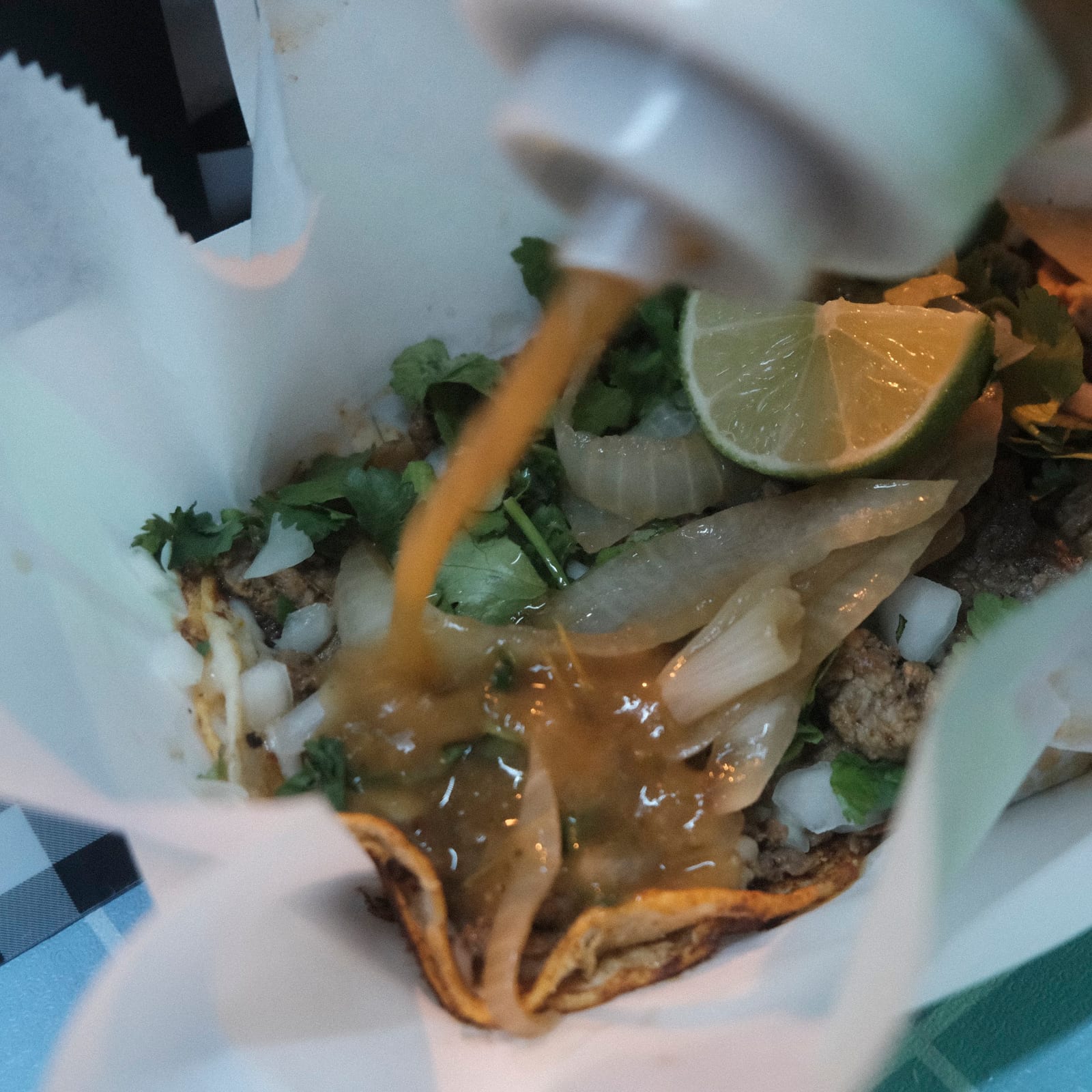 Salsa being added to a street taco at Sison Tacos